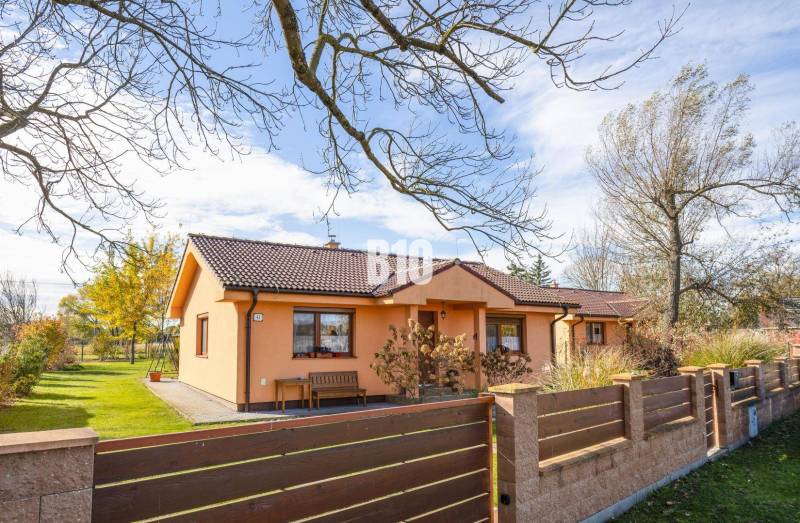 Ein Einfamilienhaus in Bíkové Humence mit einem Vorgarten und Bäumen auf einem gepflegten Grundstück.