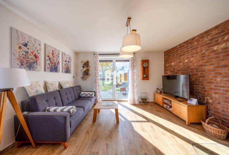 Wohnzimmer in einem Einfamilienhaus mit Sofa, Ziegelwand und Holzboden.