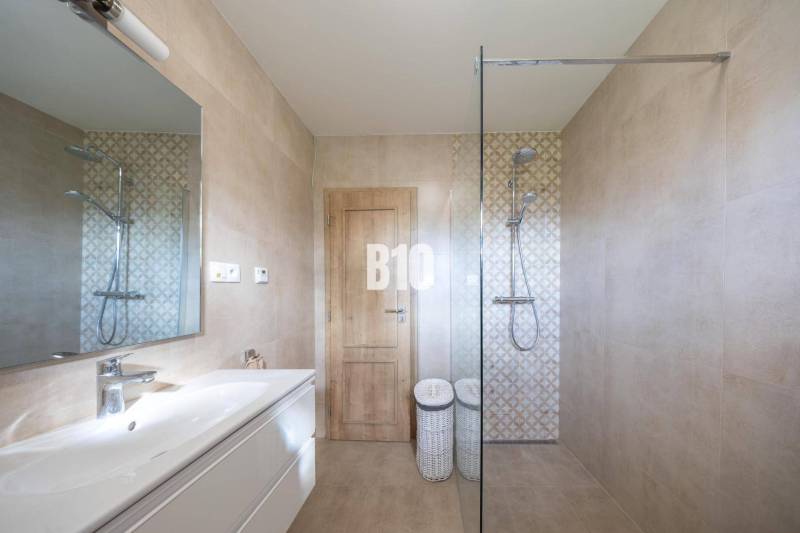 Badezimmer mit Keramikfliesen, Duschkabine und Spiegel in einem Einfamilienhaus.