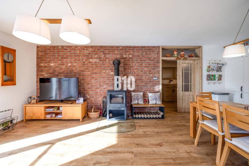 Innenraum eines Einfamilienhauses mit Ziegelwand, Ofen und Boden in Holzoptik.