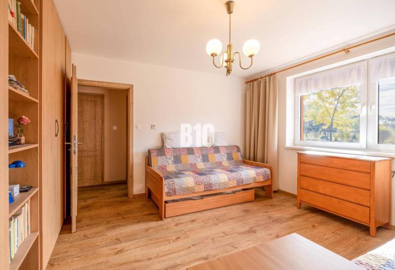 Ein Zimmer in einem Einfamilienhaus mit einem Boden in Holzoptik, einem Sofa und einer Kommode.