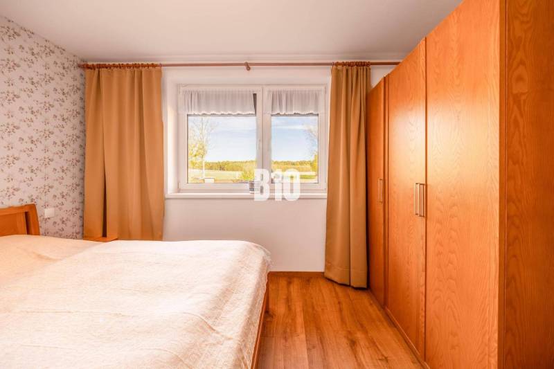 Schlafzimmer in einem Einfamilienhaus mit Holzboden und Blick aus dem Fenster.