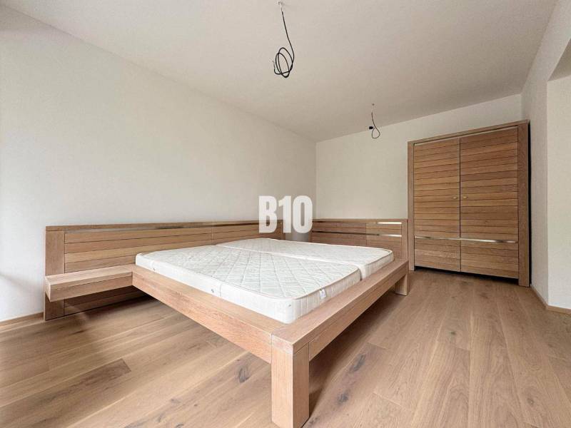 Schlafzimmer in einer 2-Zimmer-Wohnung mit einem Holzbett und einem Schrank auf einem Holzboden.