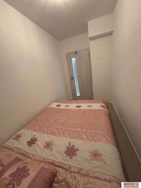 Schlafzimmer in einer 2-Zimmer-Wohnung mit einem Bett mit Blumenmotiv und hellen Wänden.