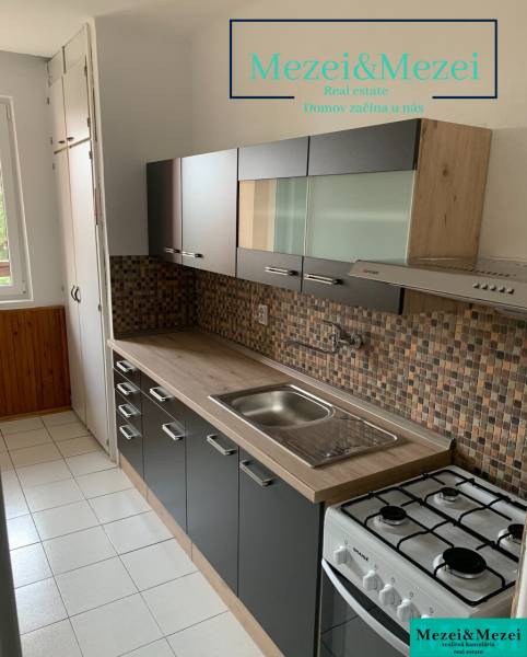 Küche in einer 2-Zimmer-Wohnung mit dunklen Möbeln und Fliesenverkleidung.