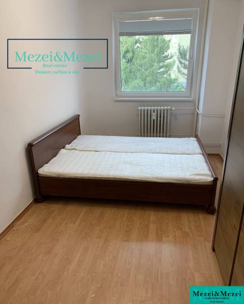 Schlafzimmer mit Bett, Holzboden, Fenster mit Blick ins Grüne.