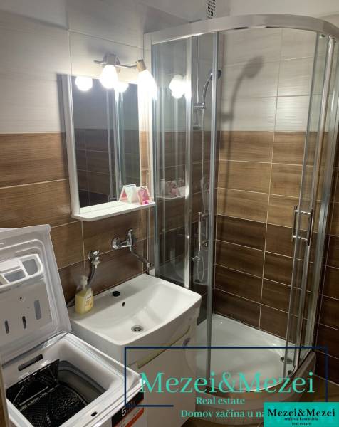 Badezimmer mit Waschbecken, Waschmaschine und Duschkabine in einer 2-Zimmer-Wohnung.