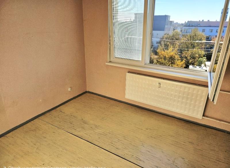 Ein Zimmer in einer 2-Zimmer-Wohnung mit einem Fenster, einem Boden in Holzoptik und einem Heizkörper.