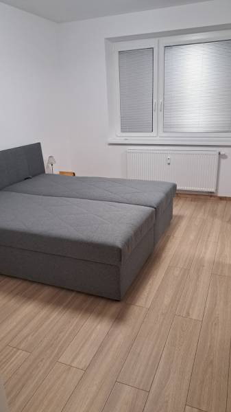 Schlafzimmer mit großem Bett und Holzboden in einer 2-Zimmer-Wohnung.