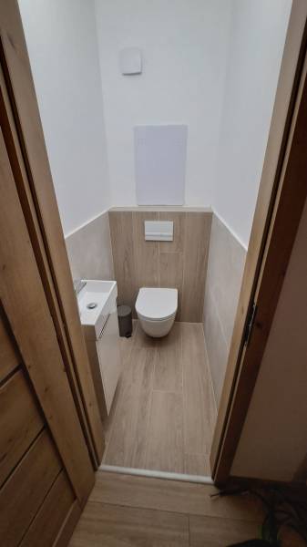 Badezimmer mit hängendem WC und Boden mit Holzdekor in einer 2-Zimmer-Wohnung.