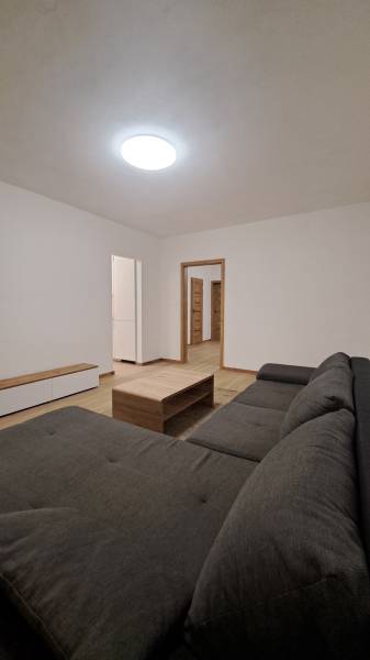 Wohnzimmer mit einem bequemen Sofa, einem Holztisch und einem Boden mit Holzdekor.