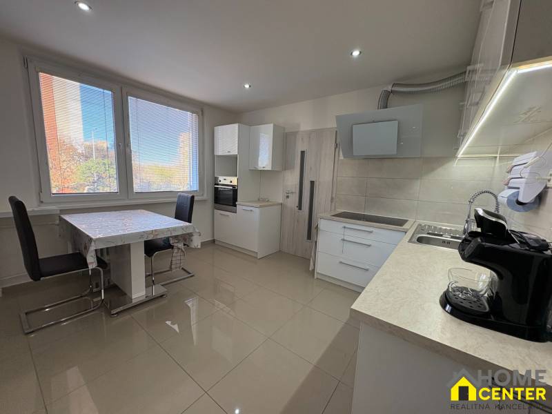 Küche einer 3-Zimmer-Wohnung mit großen Fenstern, Esstisch und hellem Boden.