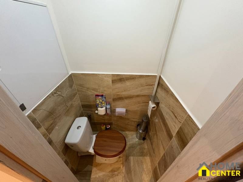 Toilette mit Wand- und Bodenfliesen in Holzoptik in einer 3-Zimmer-Wohnung.