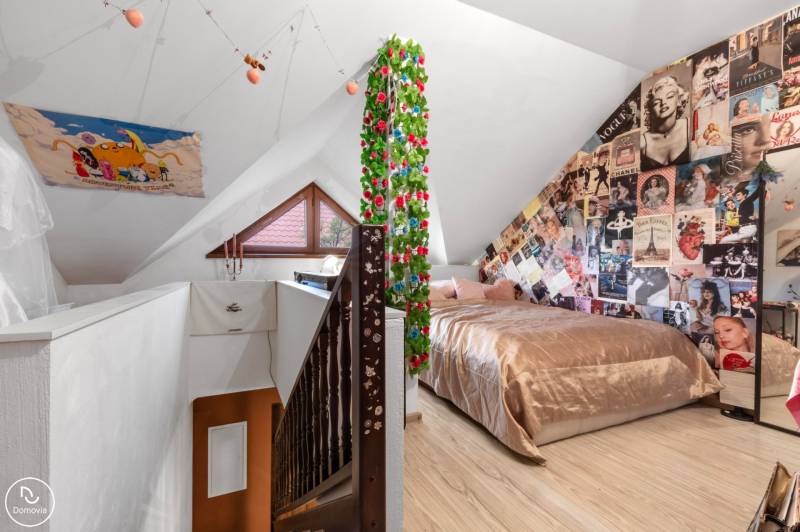 Dachzimmer in einem Einfamilienhaus mit Postern, Bett und Holzboden.