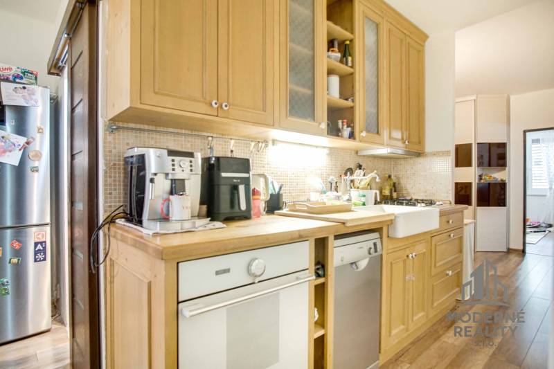 Küche mit Holzschränken und Geräten in einer 3-Zimmer-Wohnung.