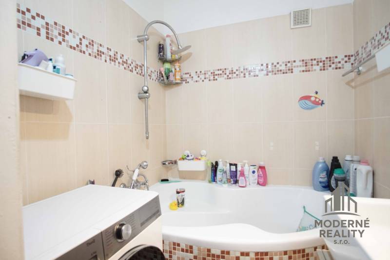 Badezimmer in einer 3-Zimmer-Wohnung mit Badewanne, Fliesen und Waschmaschine.