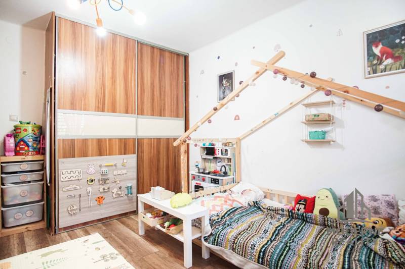 Kinderzimmer mit Schrank, Bett und Spielzeug in einer 3-Zimmer-Wohnung mit Holzboden.