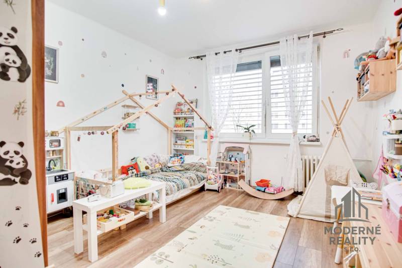 Kinderzimmer mit Pastelldekorationen, Holzboden und Spielzeug in einer 3-Zimmer-Wohnung.