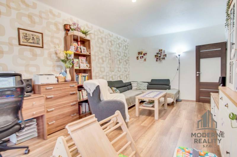 Wohnzimmer in einer 3-Zimmer-Wohnung mit Holzboden, bequemer Couch und Dekorationen.