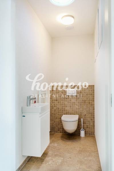 Toilette mit Waschbecken, Wänden in hellen Farben und Fliesen in einem Einfamilienhaus.