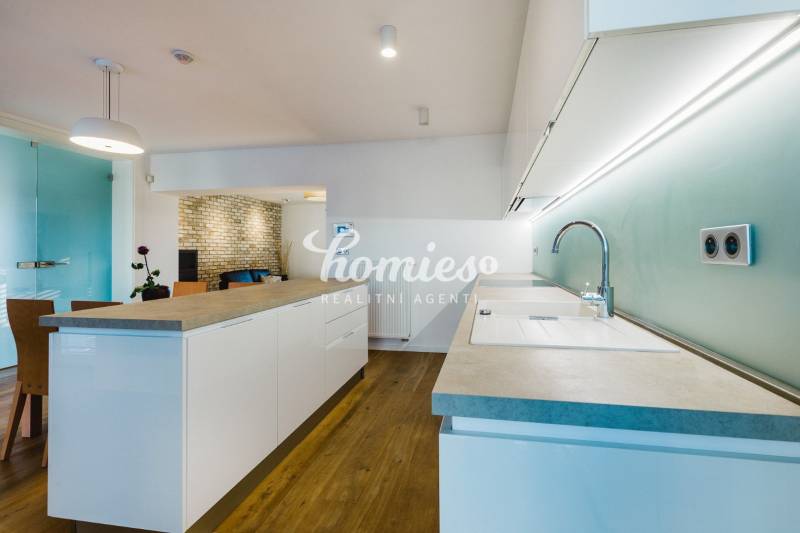 Küche mit Insel, Ziegelwand und Holzboden in einem Einfamilienhaus.