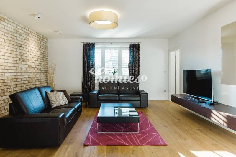 Wohnzimmer mit Ledersofa, Ziegelwand und Holzboden in einem Einfamilienhaus.