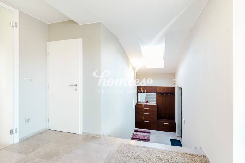 Innenraum eines Einfamilienhauses mit Fliesen und weißen Wänden, Treppe und Oberlicht.