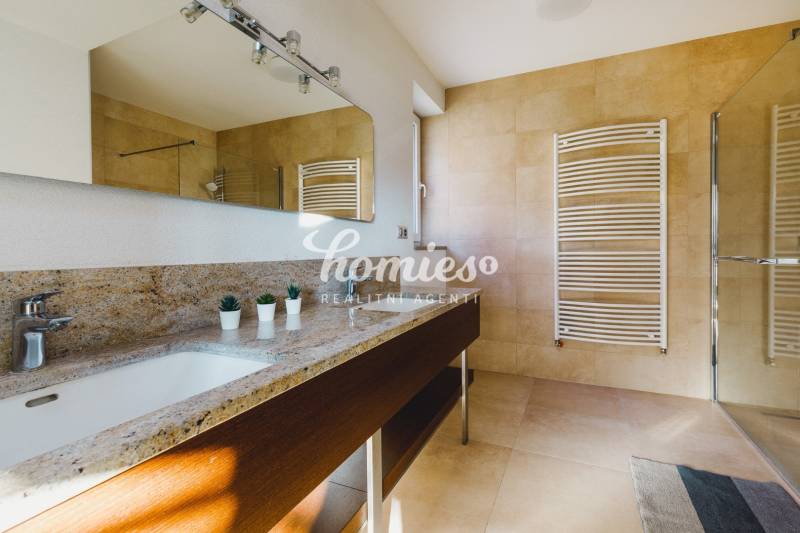 Badezimmer in einem Einfamilienhaus mit einem Waschbecken aus Stein, einem Spiegel und einem großen Fenster.