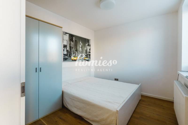 Ein Schlafzimmer in einem Einfamilienhaus mit einem einfachen Bett, einem Schrank und einem Boden mit Holzdekor.