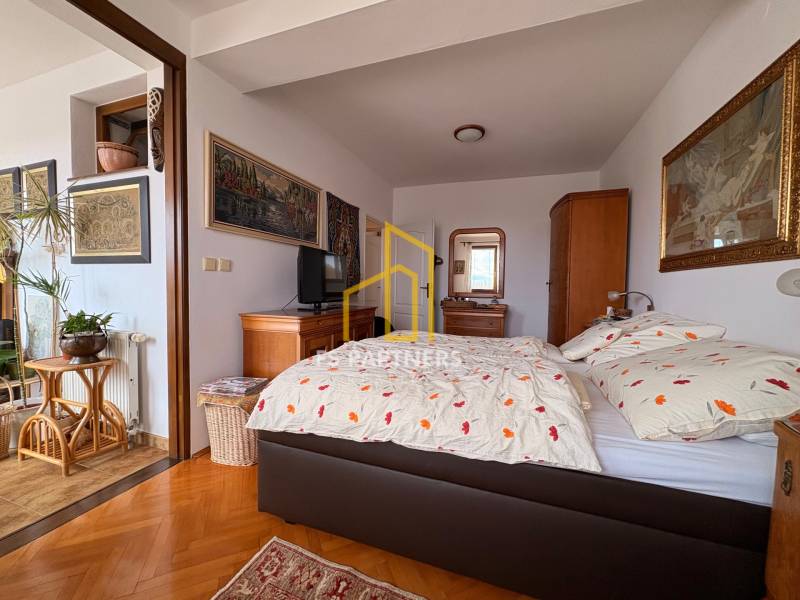 Ein Zimmer in einer Wohnung mit 5 oder mehr Zimmern mit einem Bett, Kunst an den Wänden und einem Boden in Holzoptik.