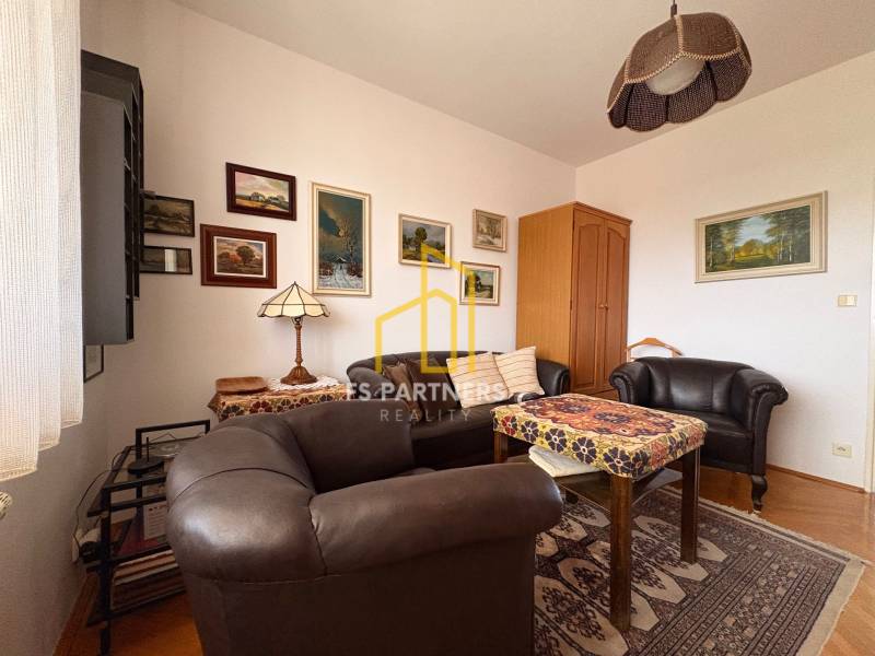 Ein Zimmer einer Fünf- oder Mehrzimmerwohnung mit Ledermöbeln und einem Boden in Holzoptik.