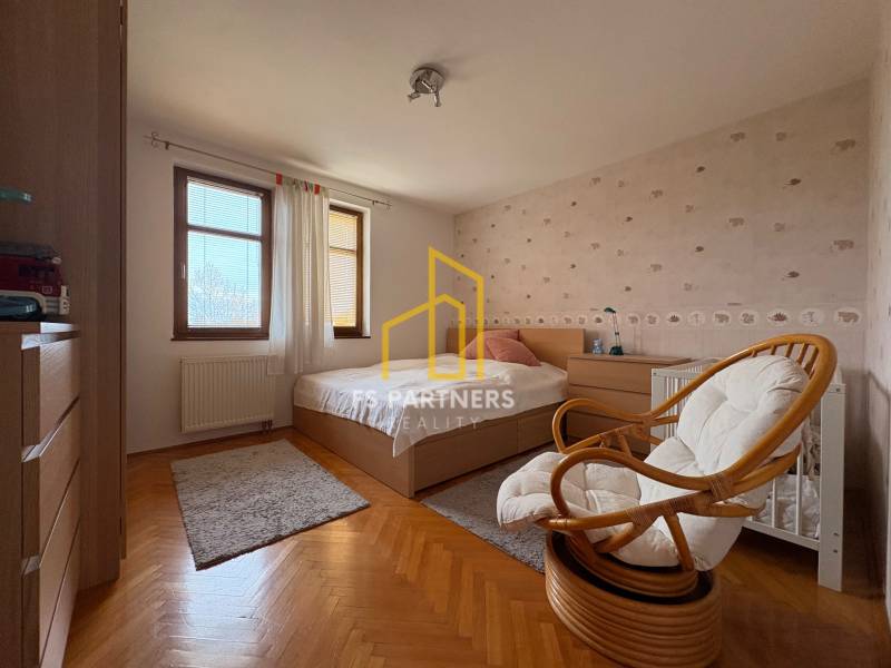 Ein Zimmer mit Bett und Sessel in einer Wohnung mit 5 oder mehr Zimmern. Boden mit Holzdekor.