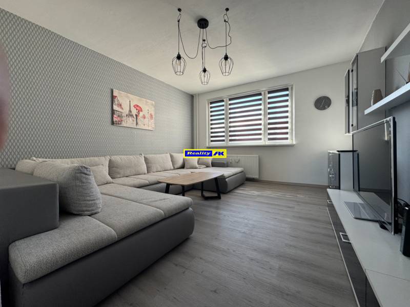 Wohnzimmer in einer 3-Zimmer-Wohnung mit einem Sofa und einem Boden in Holzoptik.