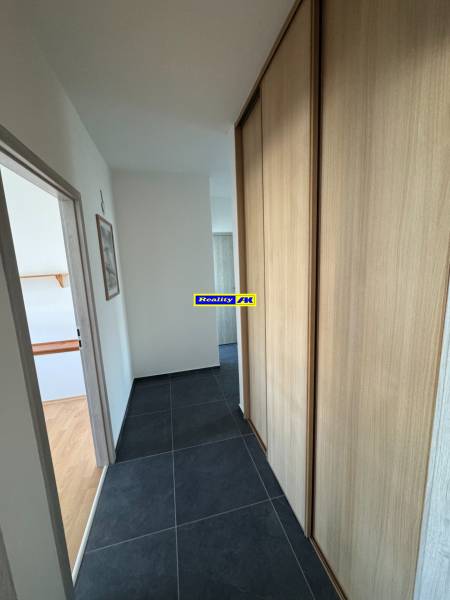 Flur in einer 3-Zimmer-Wohnung mit dunklen Fliesen und einem Einbauschrank.