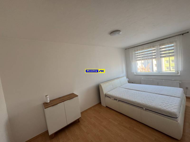 Schlafzimmer in einer 3-Zimmer-Wohnung mit Bett und Kommode, Boden mit Holzdekor.