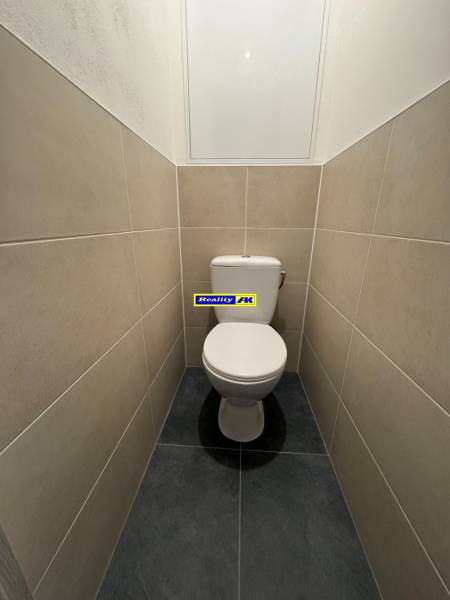 Toilette in einer 3-Zimmer-Wohnung mit hellen Fliesen und schlichtem Design.