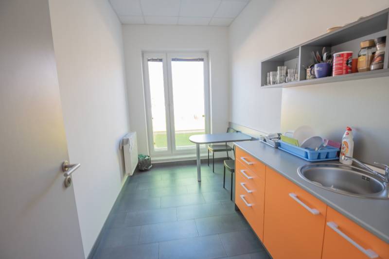 Eine Büroküche mit orangefarbenen Schränken, einem Spülbecken und einem Tisch zum Sitzen.