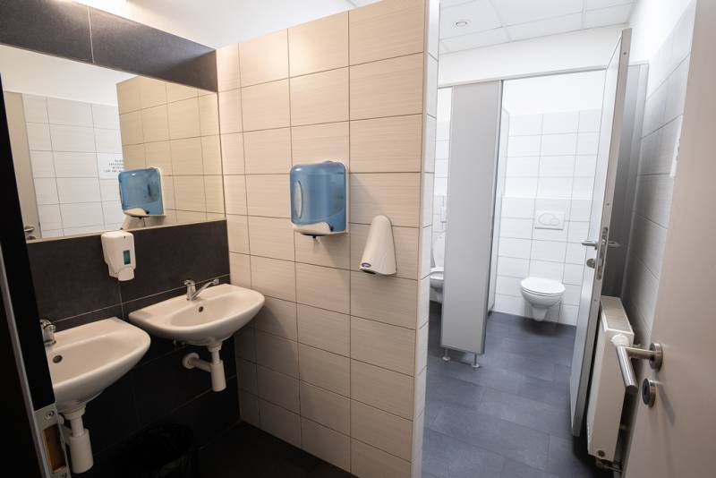 Büros: Waschbecken und Toilette in Räumen mit Fliesen und Spendern.