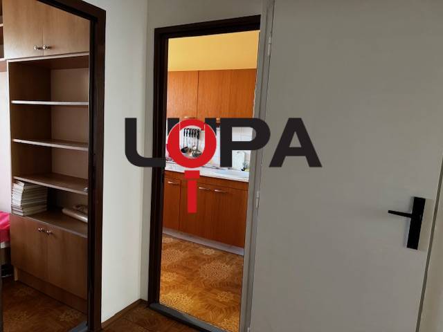 Flur mit Eingang zur Küche, Boden mit Holzdekor in einer 3-Zimmer-Wohnung.