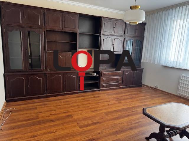 Wohnzimmer in einer 3-Zimmer-Wohnung mit Holzboden und dunklen Möbeln.