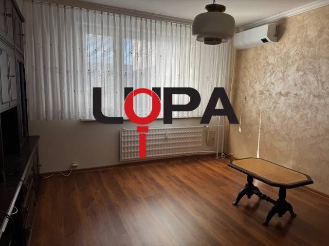 Ein Zimmer mit einem Holzboden und einem Tisch in einer 3-Zimmer-Wohnung.