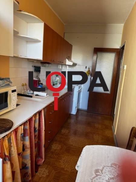 Küche in einer 3-Zimmer-Wohnung mit Holzboden, weißen Schränken, Esstisch.