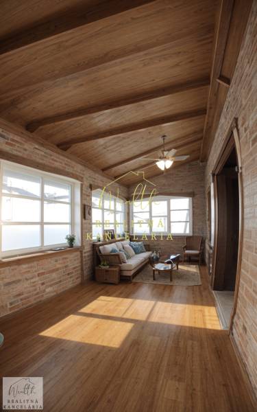 Innenraum eines Einfamilienhauses mit Ziegelwänden, Holzboden und bequemen Sitzgelegenheiten.