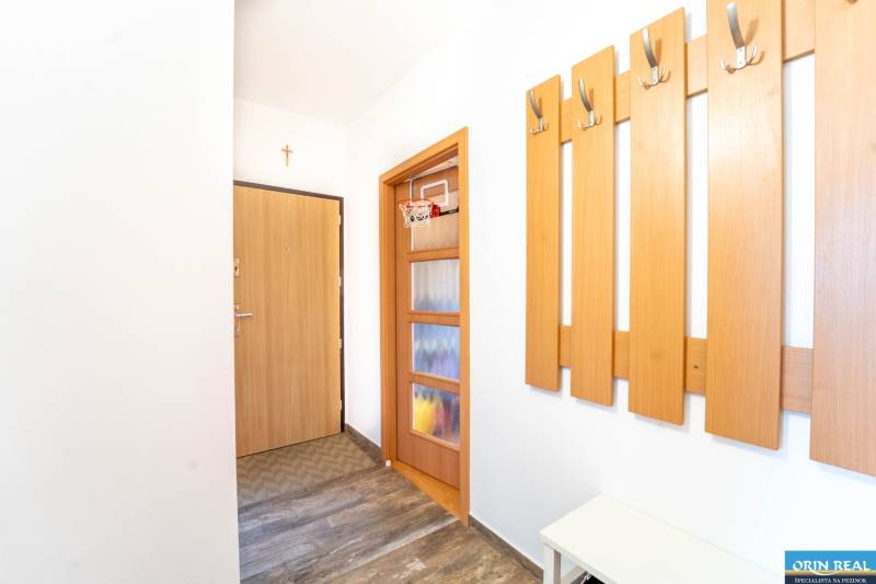 Flur mit Kleiderhaken, Türen und einem Boden in Holzoptik in einer 3-Zimmer-Wohnung.