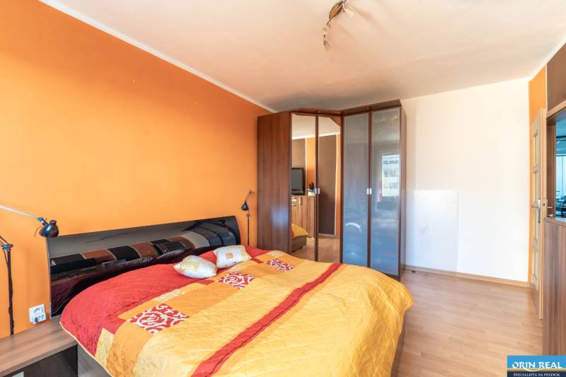 Schlafzimmer mit einem großen Bett, einem Einbauschrank und einem Bodenbelag in Holzoptik in einer 3-Zimmer-Wohnung.