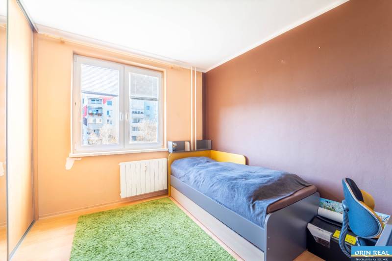 Kinderzimmer mit Bett und grünem Teppich in einer 3-Zimmer-Wohnung.