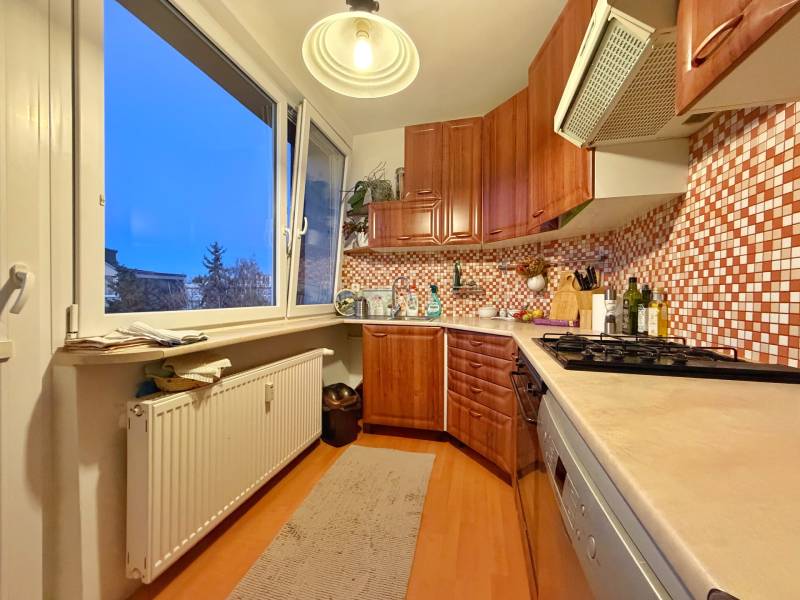 Küche in einer 3-Zimmer-Wohnung mit hellen Möbeln und einem Boden in Holzoptik.