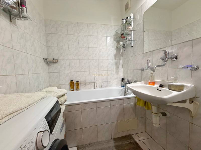 Badezimmer in einer 3-Zimmer-Wohnung mit Waschmaschine, Waschbecken und Badewanne, gefliest mit hellen Fliesen.