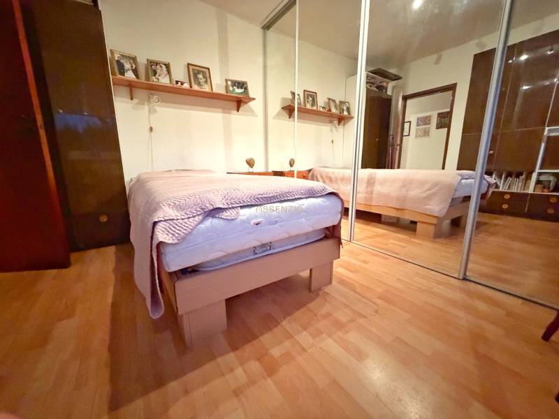 Schlafzimmer in einer 3-Zimmer-Wohnung mit Bett, Spiegelschrank und Boden mit Holzdekor.