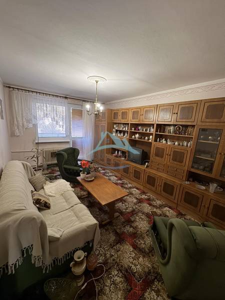 Wohnzimmer in einer 3-Zimmer-Wohnung mit einer Wohnwand aus Holz und bequemen Sitzgelegenheiten.